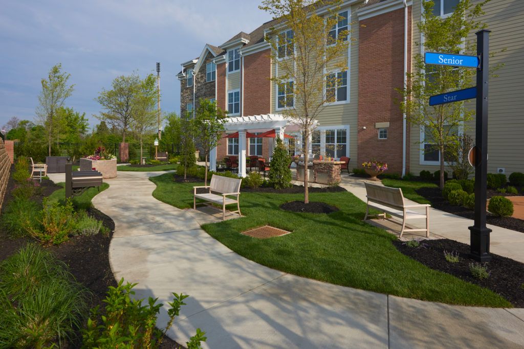 A well-maintained apartment building with landscaped grounds and benches.