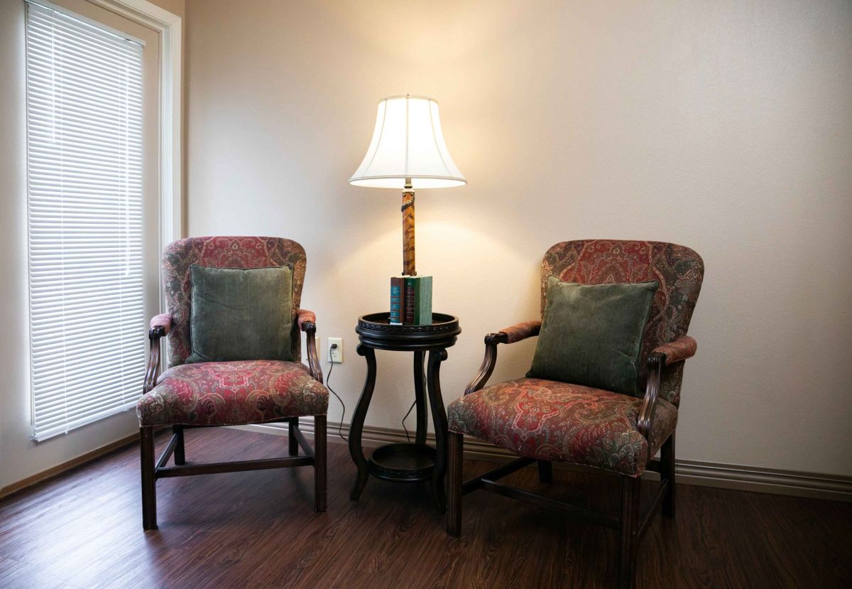 A cozy seating arrangement with two chairs and a lamp in a living room setting.