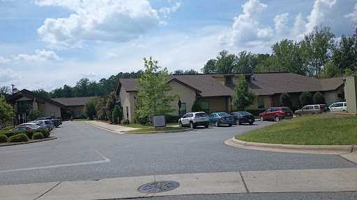 A view of a residential area featuring multiple buildings and parked cars under a partly cloudy sky.