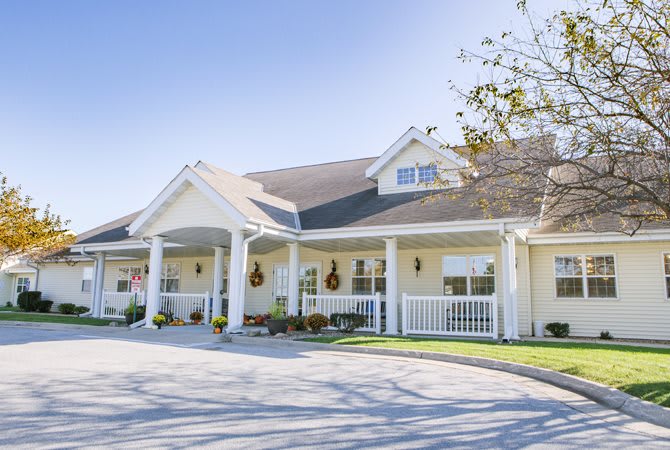 A large white residential building with a spacious porch and landscaped surroundings.