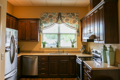 A beautifully designed kitchen featuring dark wood cabinets, modern appliances, and a cozy window area with floral curtains.