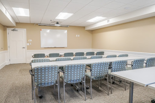 A spacious and organized meeting room equipped with chairs and tables, ready for a conference or group discussion.
