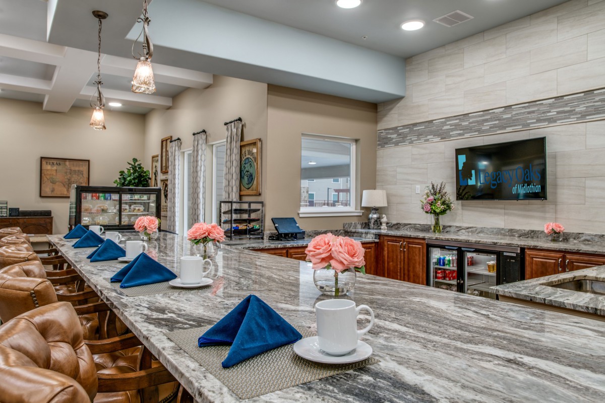 A modern kitchen with a marble countertop set for dining, featuring elegant decor and fresh flowers.
