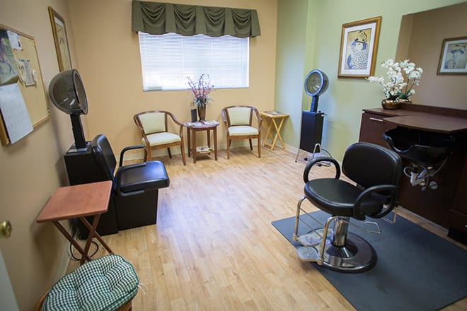 A cozy salon room featuring a waiting area with chairs and a styling station.