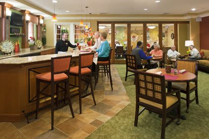 A cozy caf interior with people socializing at the bar and seated at tables.