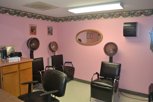 A cozy hair salon featuring pink walls, styling chairs, and hair dryers.