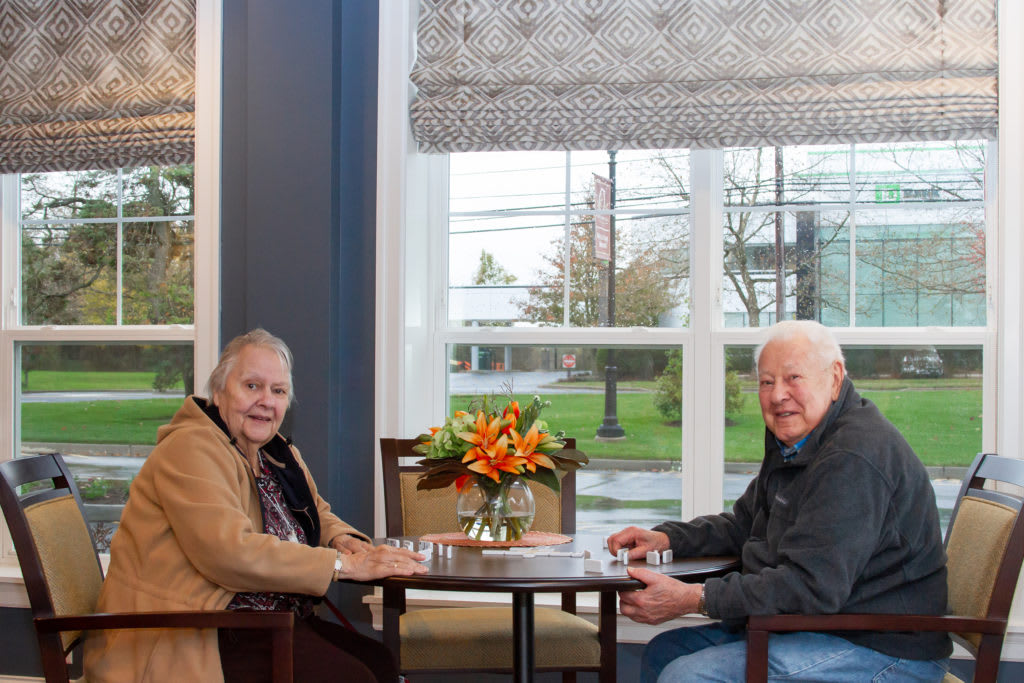 Two seniors sitting at a table in a cozy cafe, enjoying each other's company.