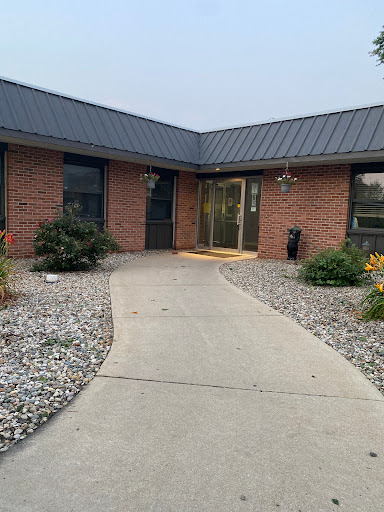 A welcoming entrance to a modern brick building surrounded by landscaped gardens and a concrete pathway.