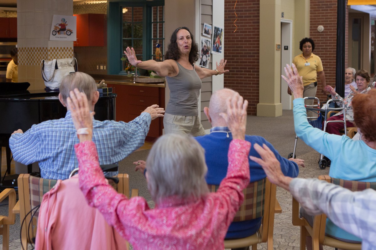 A group of seniors participating in a seated exercise class indoors.