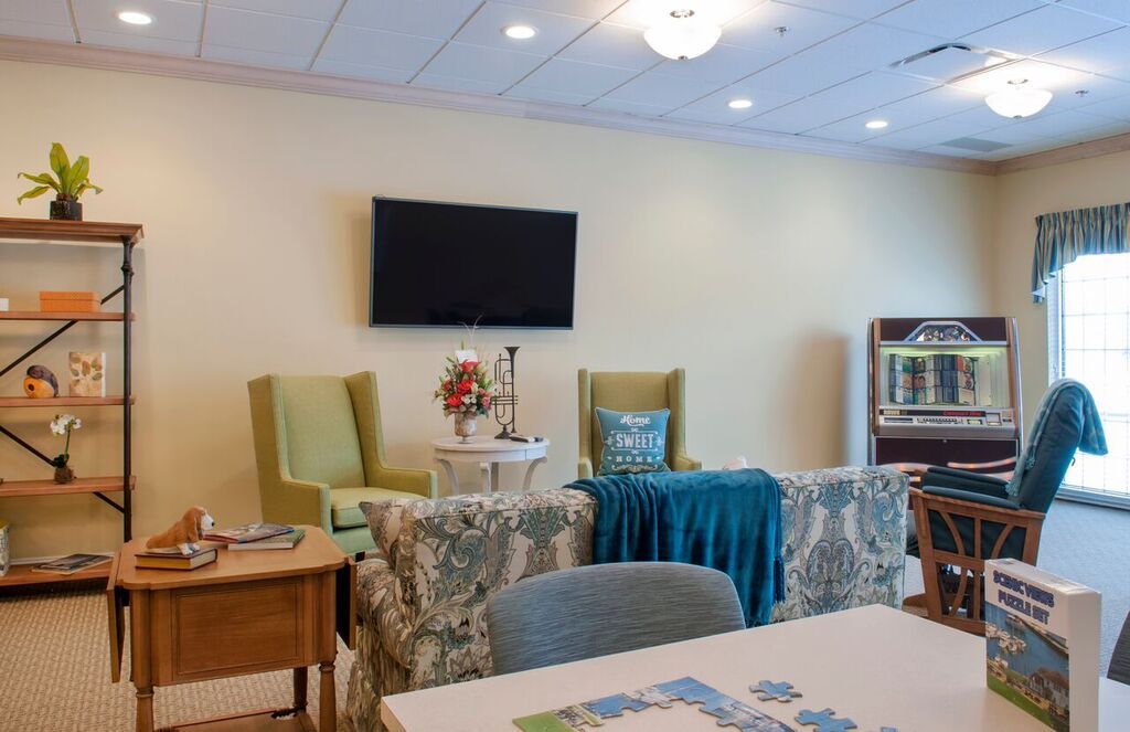 A cozy living room with a mounted television, two armchairs, and decorative elements.