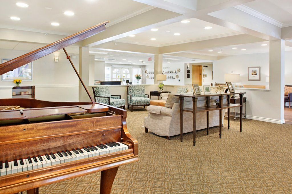 A spacious living room featuring a grand piano and elegant furniture.