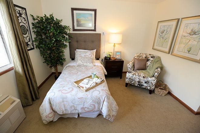 A cozy bedroom with a single bed, armchair, and decorative elements.