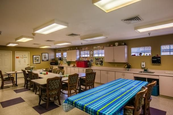 A well-lit communal kitchen and dining area with tables, chairs, and kitchen cabinets.