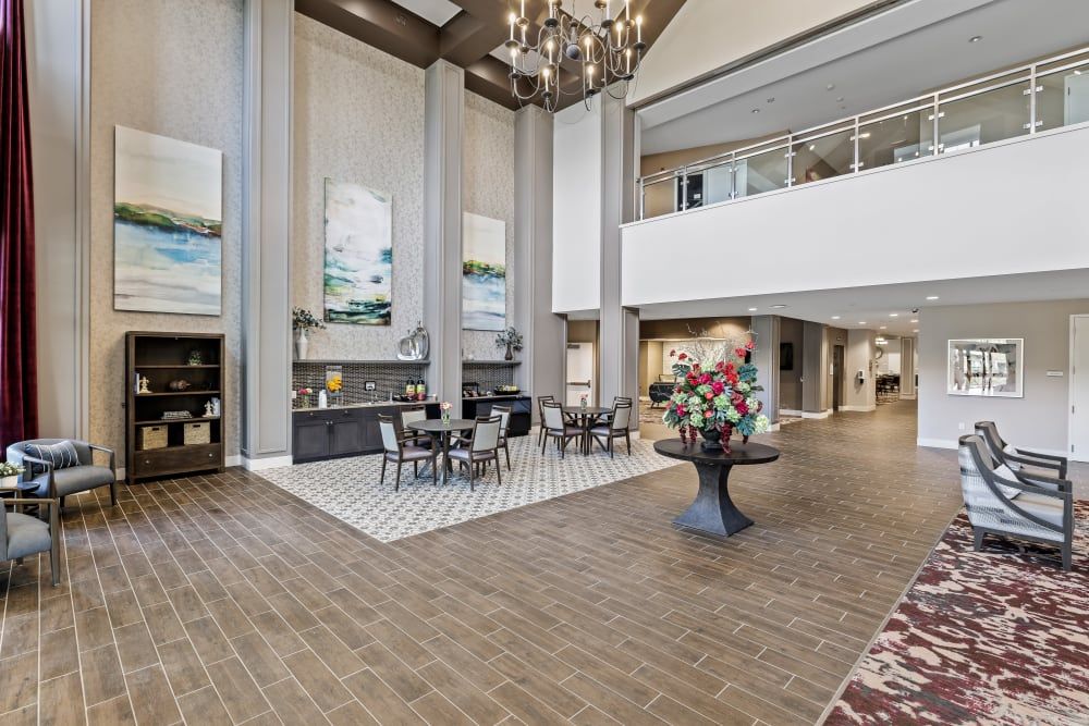 A spacious, modern lobby with a high ceiling and elegant chandelier, featuring comfortable seating and tasteful decor.