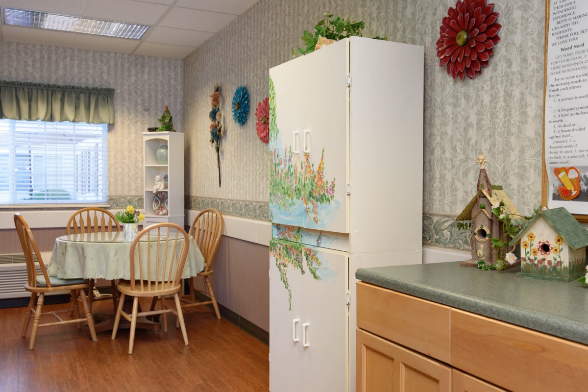 A cozy kitchen and dining area with a table, chairs, and decorated refrigerator.