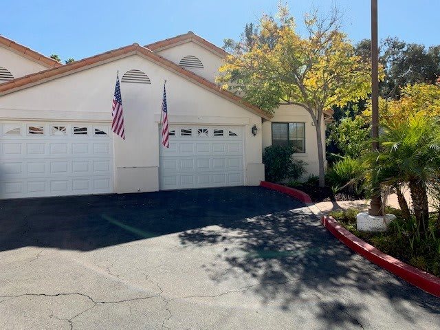 A sunny day view of a house with two garages and American flags displayed.