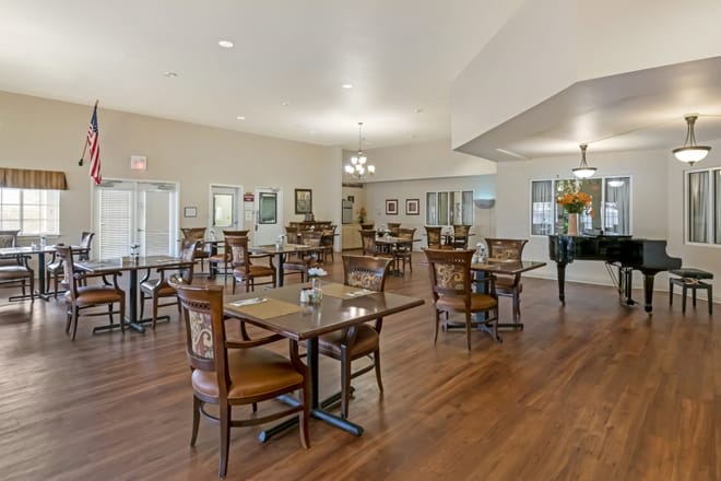 A spacious dining area with tables and chairs, featuring hardwood floors and elegant lighting.