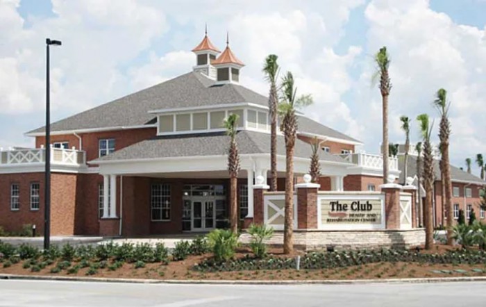 A clubhouse with brick architecture, surrounded by palm trees and landscaping.