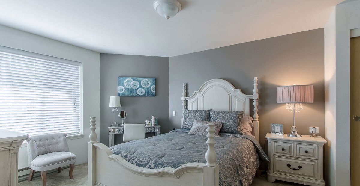 A stylish bedroom with gray walls, featuring a cozy bed and elegant decor.