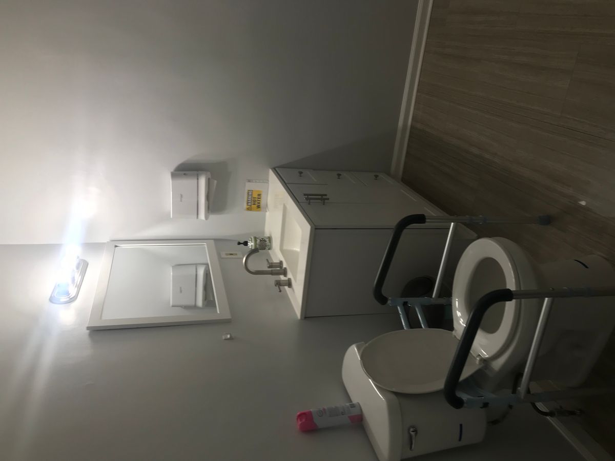 An accessible bathroom equipped with a toilet, sink, and handrails.