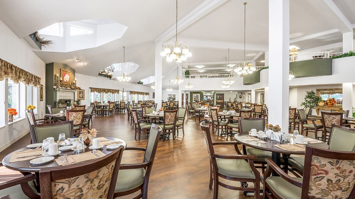 A spacious and elegantly designed restaurant dining area with wooden floors and chandeliers.