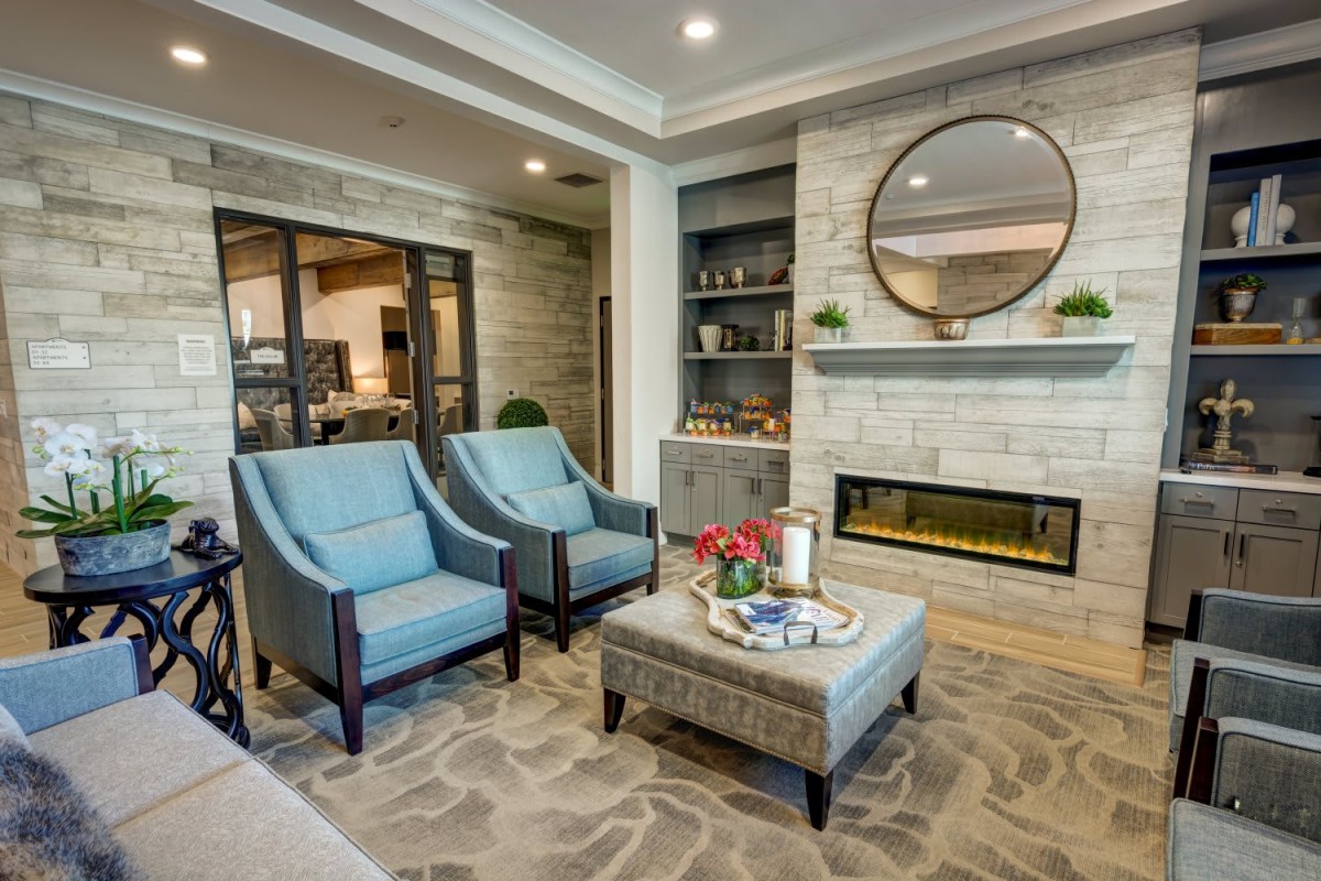 A cozy and modern living room featuring blue armchairs, a geometric-patterned rug, and a contemporary fireplace.