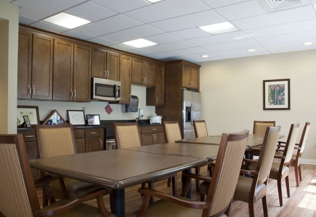 A conference room with a kitchenette and large meeting table surrounded by chairs.