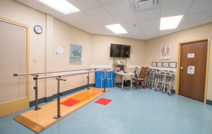 A physical therapy room equipped with parallel bars and various rehabilitation tools.