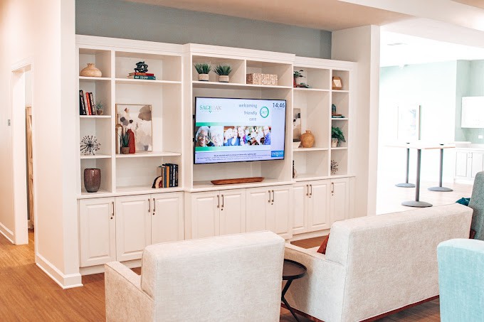 A cozy living room featuring a built-in entertainment center with open shelves, displaying various decorative items and a large television.