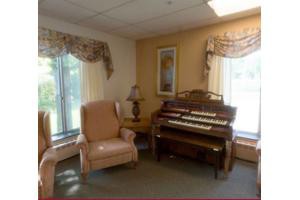 A cozy room featuring an organ, a comfortable chair, and large windows letting in natural light.