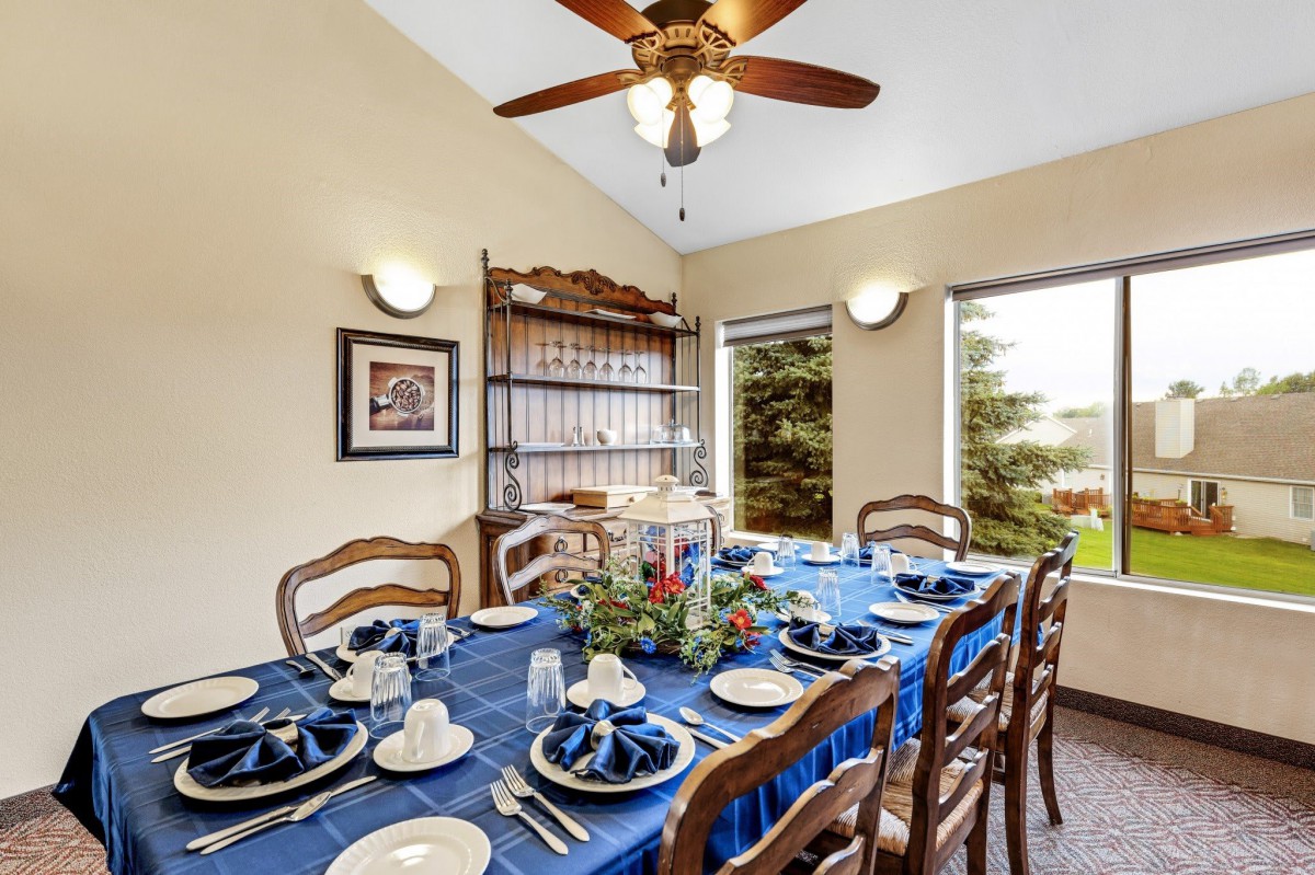 A dining room with a table set for a meal, featuring a blue tablecloth and floral centerpiece.
