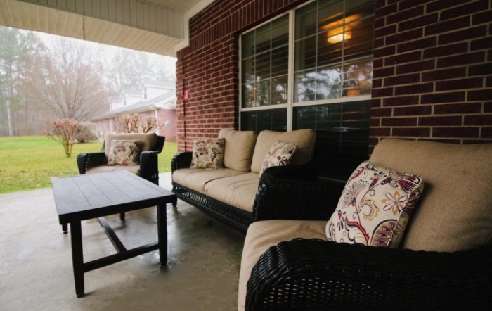 A cozy outdoor patio with comfortable seating and a table set against a brick wall.