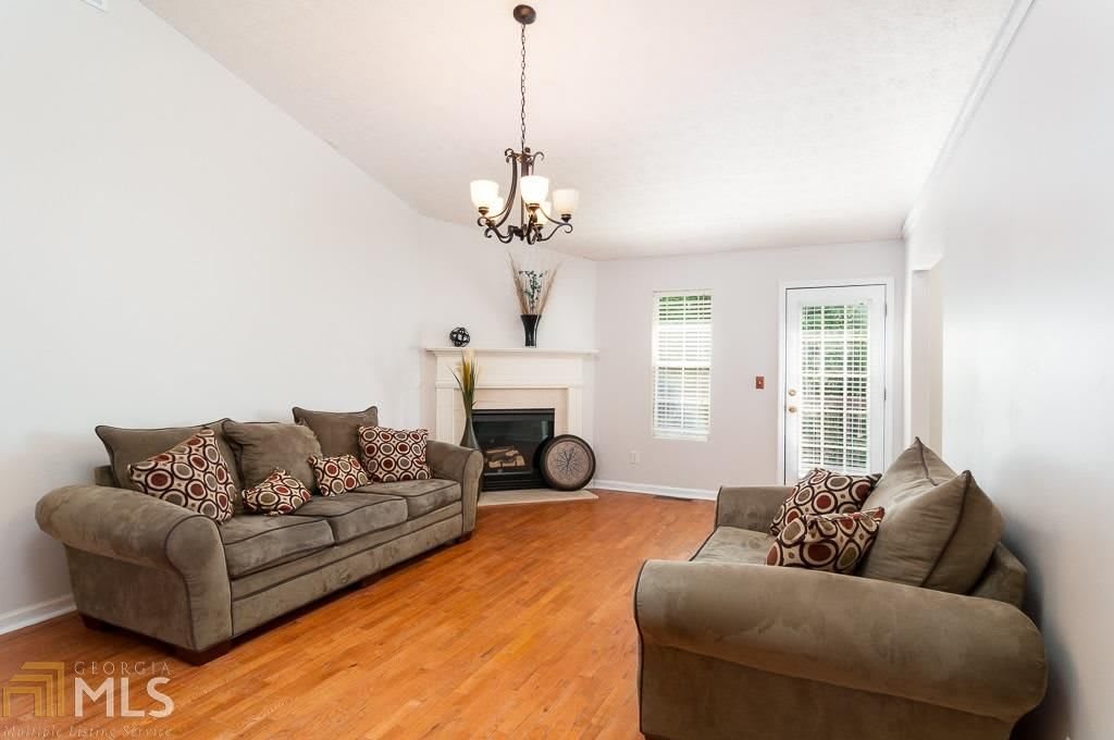 A cozy living room with a chandelier, comfortable sofas, and a fireplace.