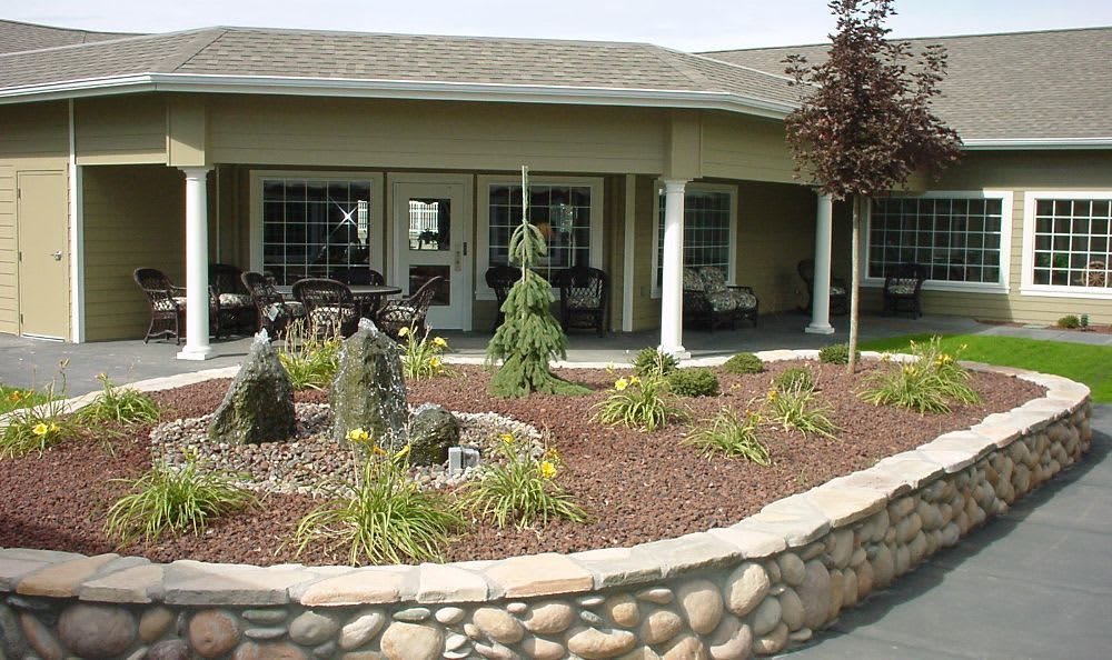 A beautifully landscaped patio area with shrubs and stone edging.