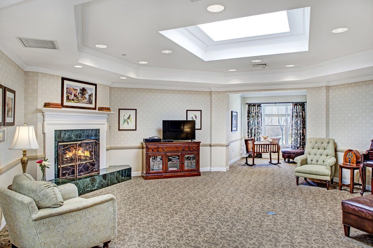 A spacious living room with a fireplace, television, and seating area under a skylight.