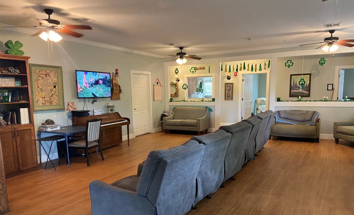 A cozy living room with a long sofa, piano, and TV.