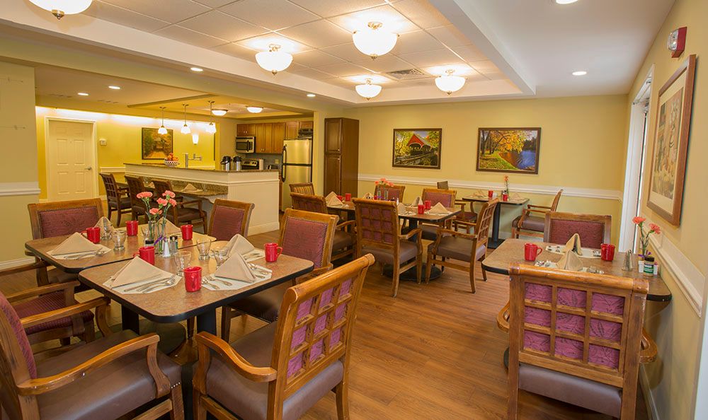 An inviting dining room with neatly arranged tables and chairs, warm lighting, and decorative artwork on the walls.