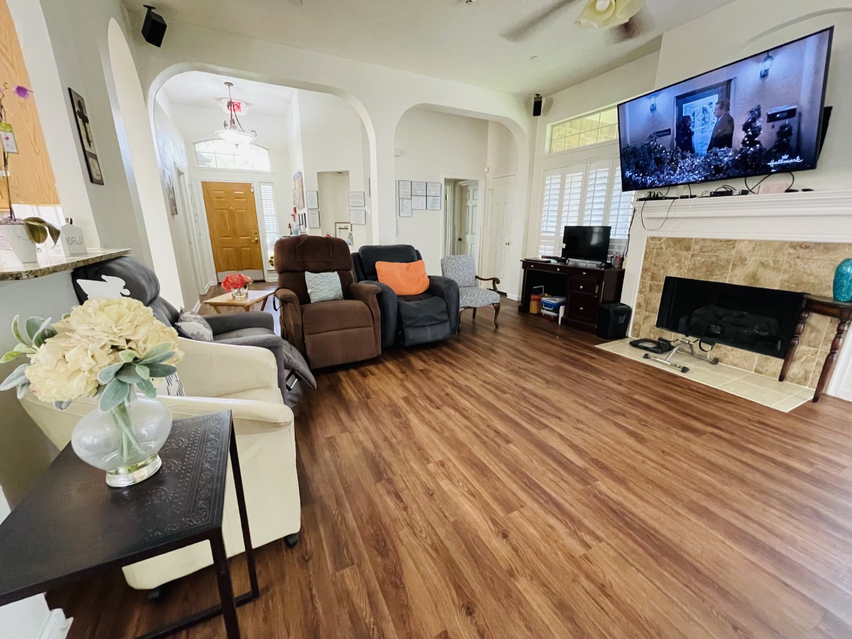 A cozy living room with hardwood floors, featuring a fireplace and a mounted TV.