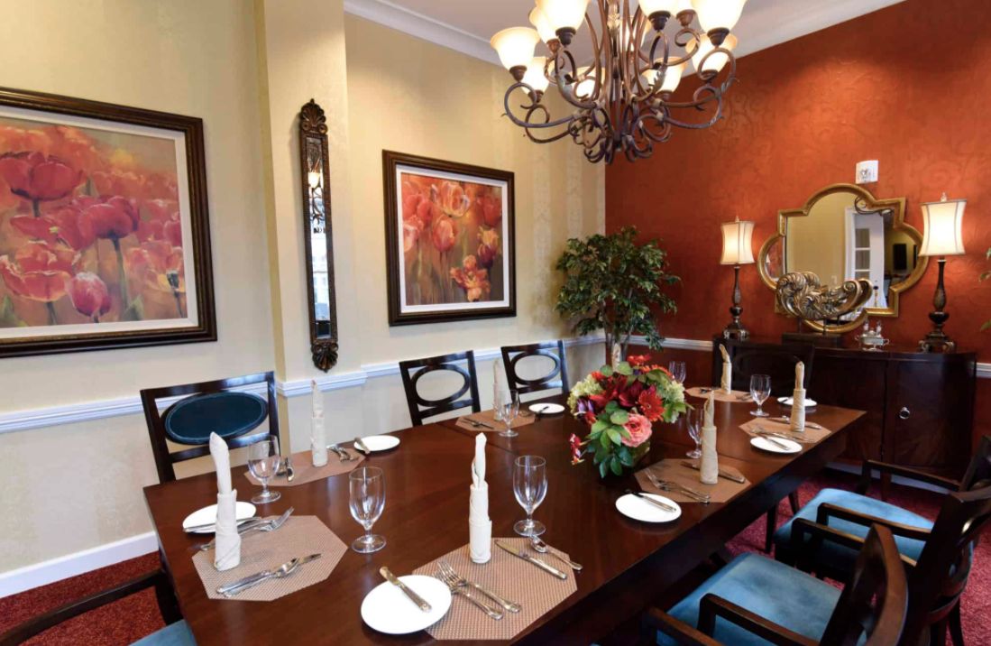 An elegantly decorated dining room with a set table and a chandelier overhead.