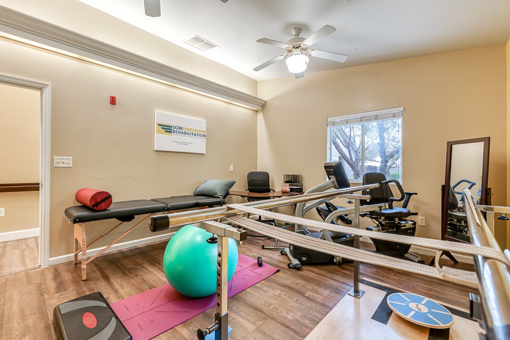 A rehabilitation room equipped with exercise equipment including parallel bars and an exercise ball.