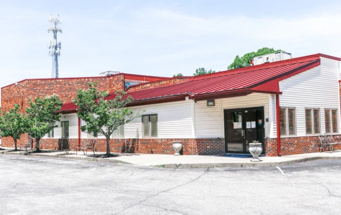 A small restaurant with a red roof and adjacent parking lot.