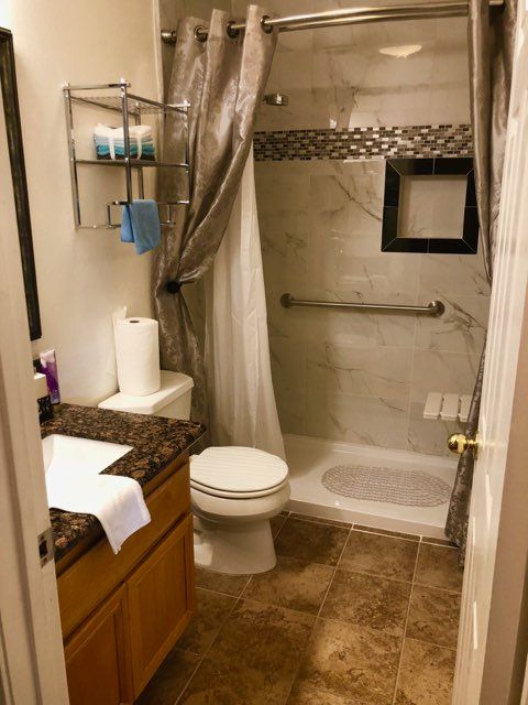 A modern bathroom with a shower, toilet, and sink.