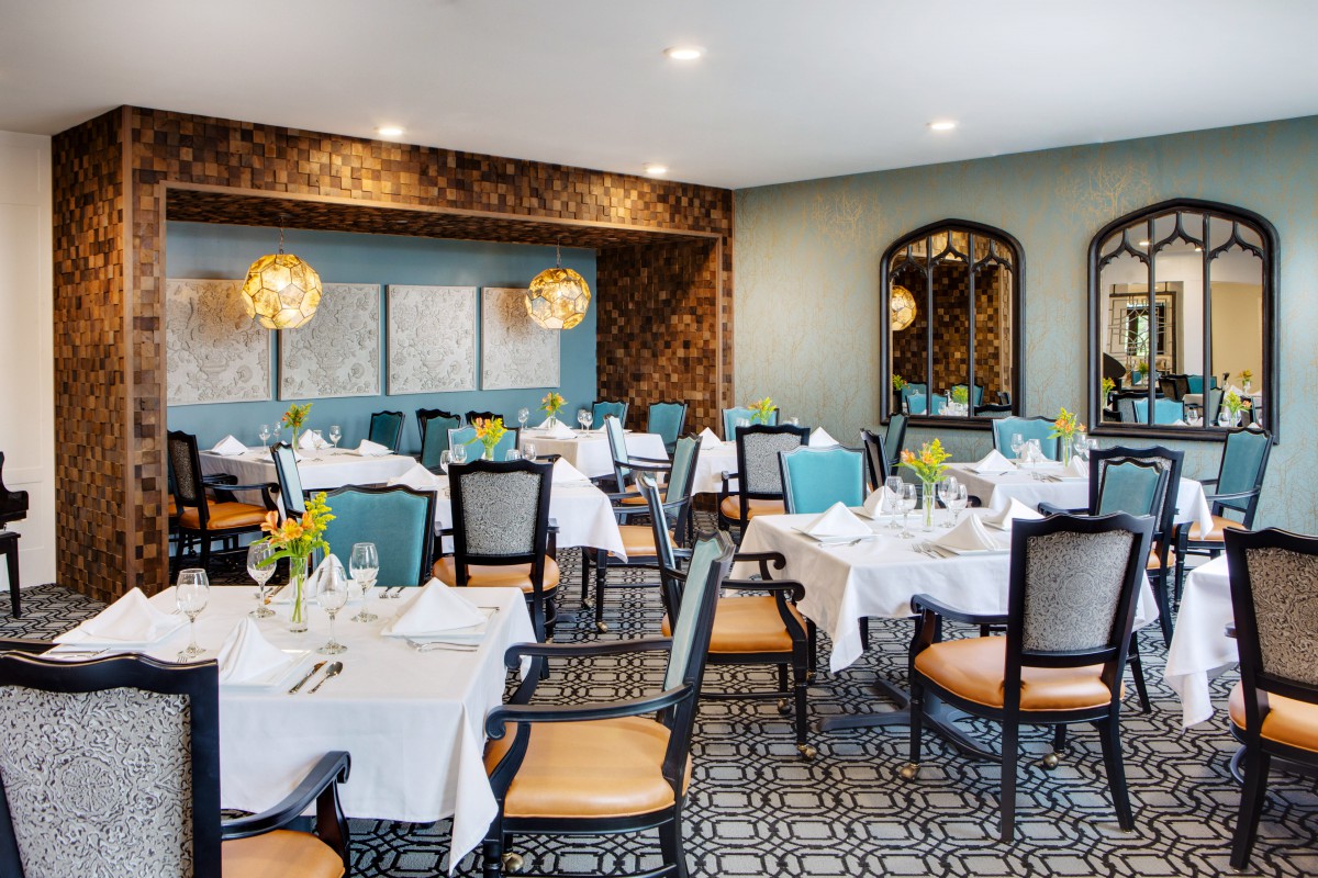 A stylish restaurant dining room with elegantly set tables and comfortable seating.