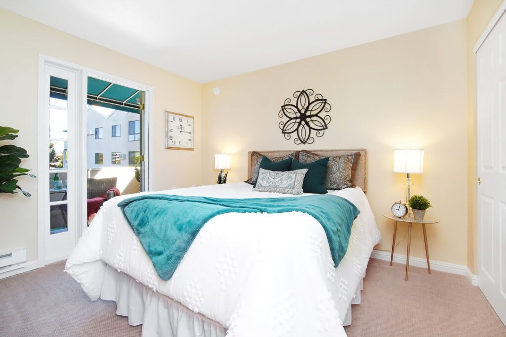 A cozy bedroom with a neatly made bed, decorative pillows, and wall art.