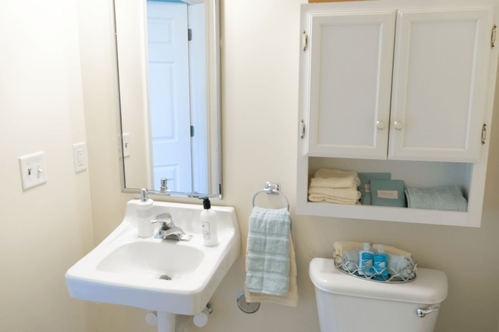 A clean and organized bathroom with a sink, mirror, and cabinet.
