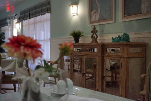 A beautifully designed dining room featuring elegant wooden furniture, decorative plants, and artworks.