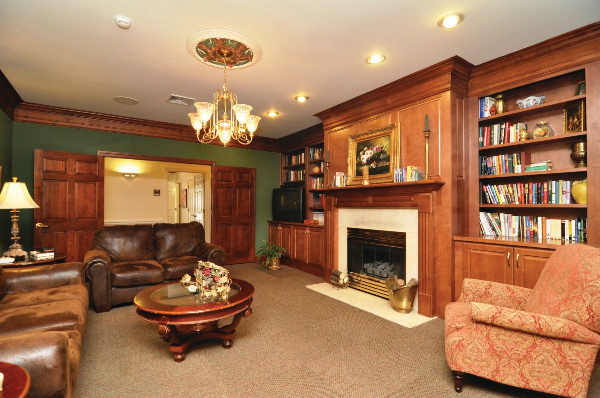 A cozy living room with a fireplace, wood paneling, and elegant decor.