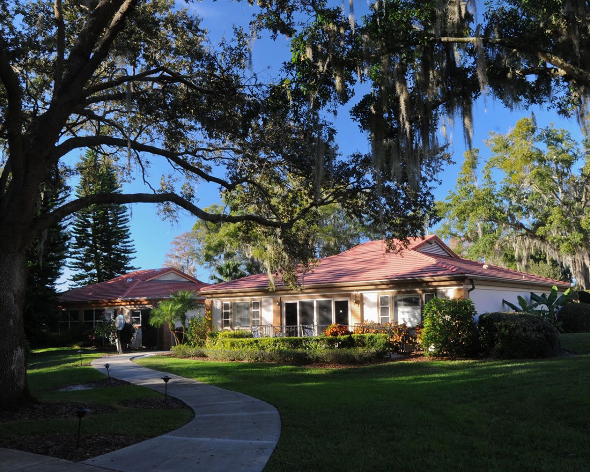 A charming house surrounded by lush greenery and a winding pathway under a clear blue sky.