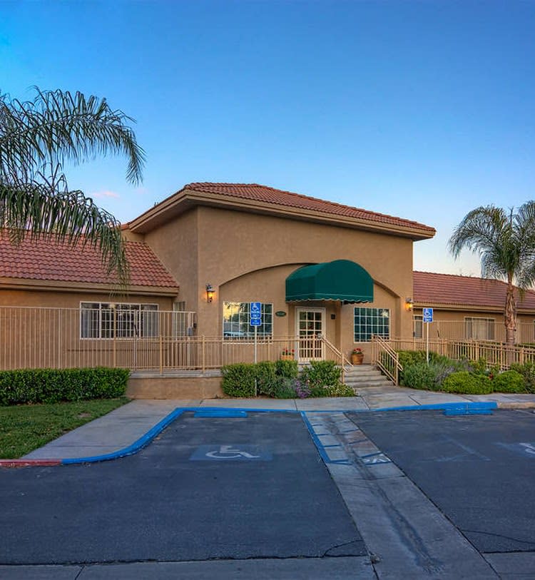 A suburban residential building with a driveway and palm trees.