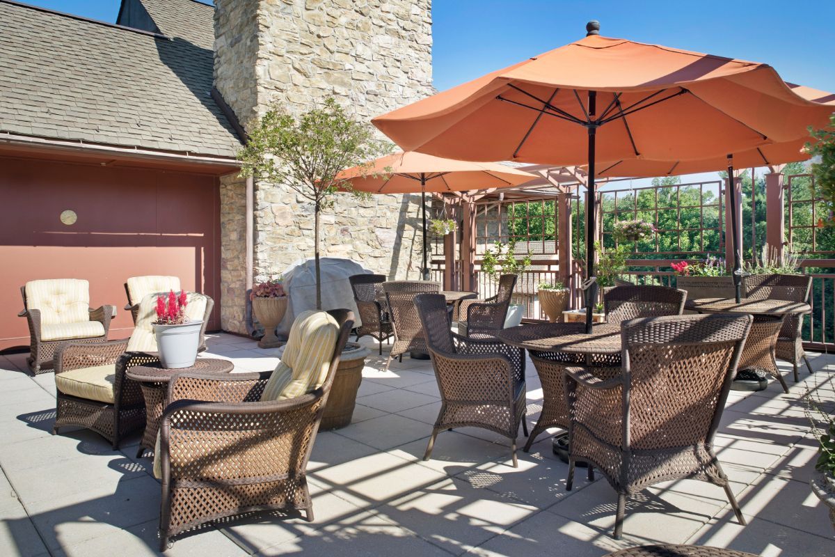 A sunny patio with wicker furniture and orange umbrellas.